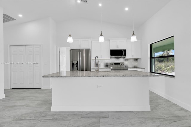 kitchen with a sink, light stone countertops, a center island with sink, stainless steel appliances, and white cabinets