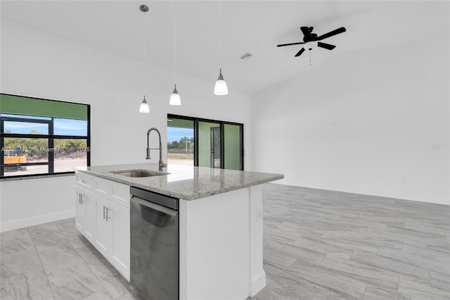kitchen featuring a kitchen island with sink, white cabinetry, a sink, light stone counters, and hanging light fixtures