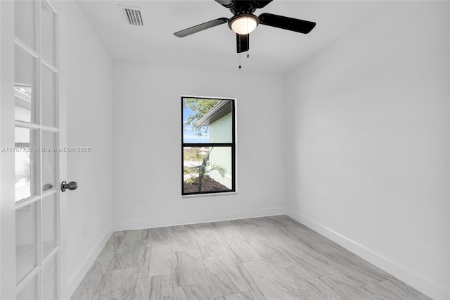 spare room featuring baseboards, ceiling fan, and visible vents