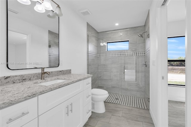 full bath featuring toilet, vanity, a stall shower, and visible vents