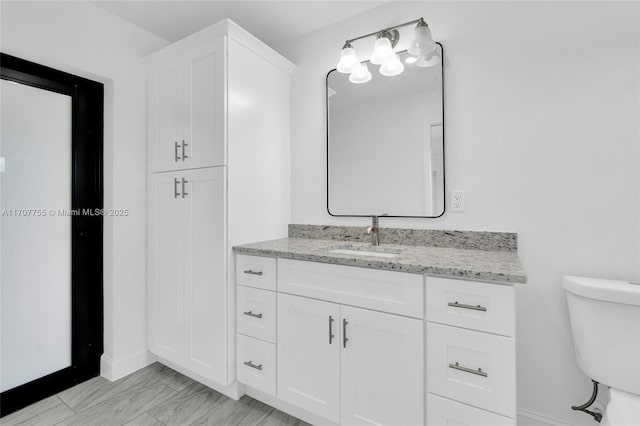 bathroom with baseboards, marble finish floor, toilet, and vanity