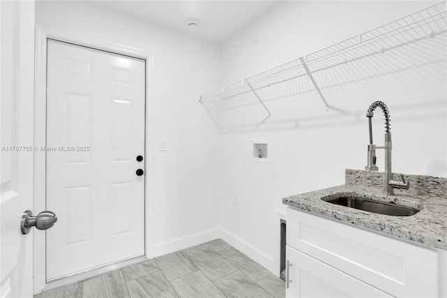laundry area with baseboards, cabinet space, a sink, and hookup for a washing machine