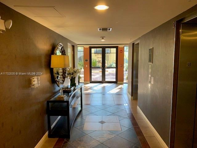 hall featuring tile patterned flooring and french doors