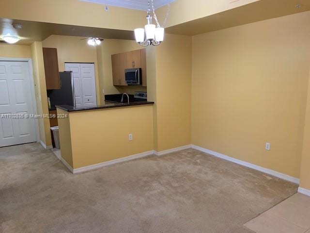 kitchen with light carpet, hanging light fixtures, a notable chandelier, and appliances with stainless steel finishes