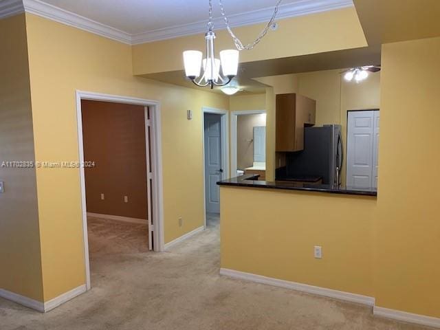 kitchen with light carpet, ceiling fan with notable chandelier, hanging light fixtures, ornamental molding, and stainless steel refrigerator