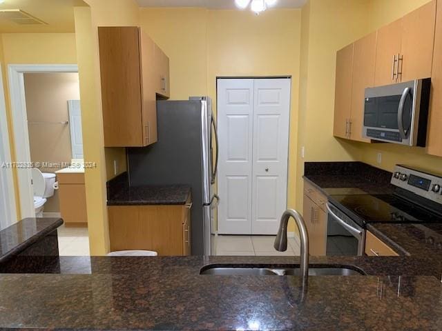 kitchen featuring light brown cabinets, dark stone countertops, sink, and appliances with stainless steel finishes