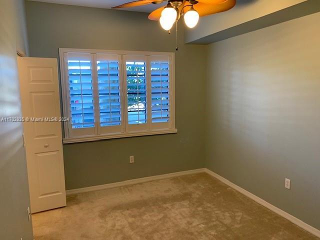 spare room featuring light colored carpet and ceiling fan