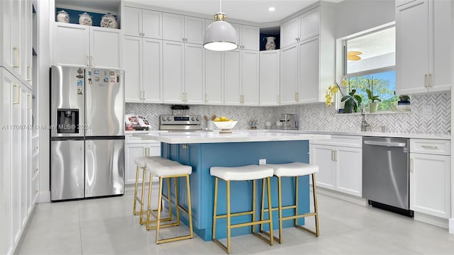 kitchen featuring hanging light fixtures, stainless steel appliances, a kitchen island, decorative backsplash, and white cabinets