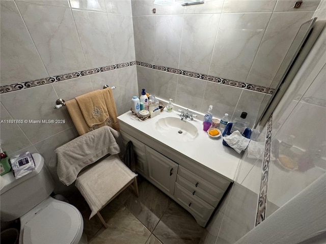 bathroom featuring toilet, vanity, tile walls, and tile patterned floors