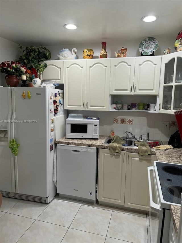 kitchen with white appliances, white cabinets, decorative backsplash, light stone counters, and light tile patterned floors