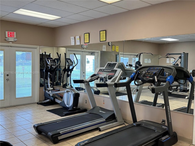 exercise room with a paneled ceiling, french doors, and light tile patterned flooring