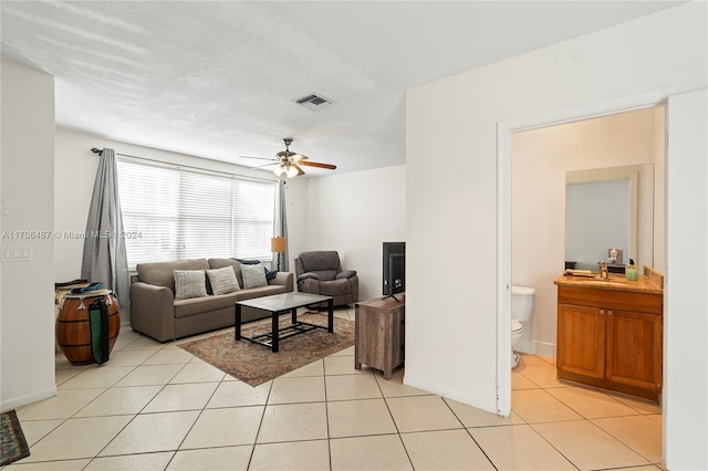 tiled living room with ceiling fan and sink