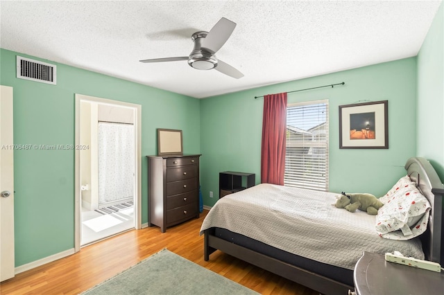 bedroom featuring ensuite bath, ceiling fan, hardwood / wood-style floors, and a textured ceiling