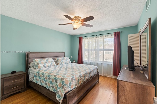 bedroom featuring ceiling fan, a closet, light hardwood / wood-style floors, and a textured ceiling