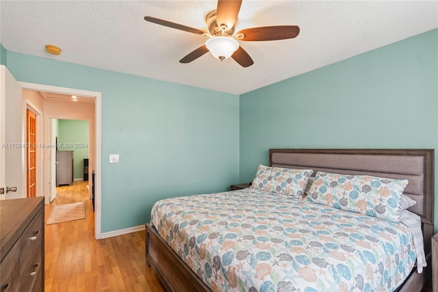 bedroom featuring ceiling fan, light hardwood / wood-style flooring, and a textured ceiling