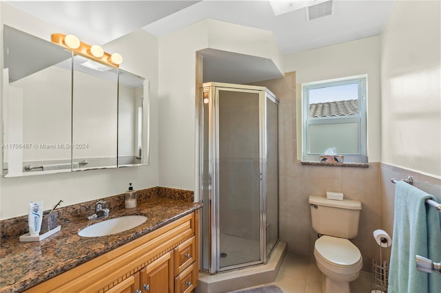 bathroom with tile patterned flooring, vanity, tile walls, and walk in shower