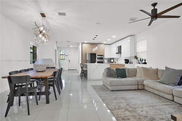 living room with ceiling fan with notable chandelier, a wealth of natural light, and light tile patterned flooring