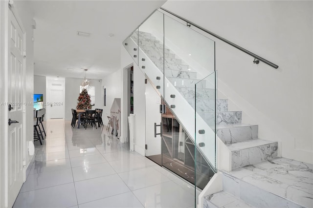 staircase featuring tile patterned flooring and an inviting chandelier