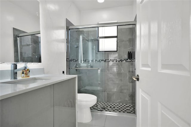 bathroom featuring tile patterned floors, vanity, toilet, and a shower with shower door