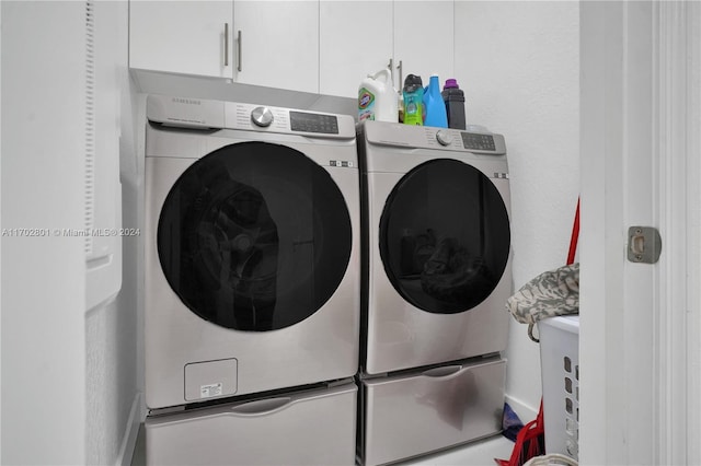 clothes washing area featuring cabinets and separate washer and dryer