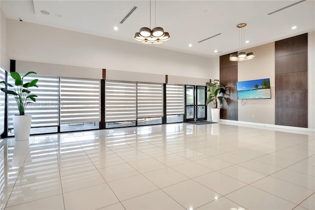 interior space featuring a towering ceiling, light tile patterned flooring, and an inviting chandelier