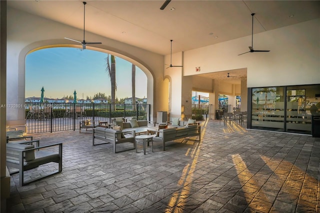 patio terrace at dusk featuring a water view, an outdoor living space, and ceiling fan