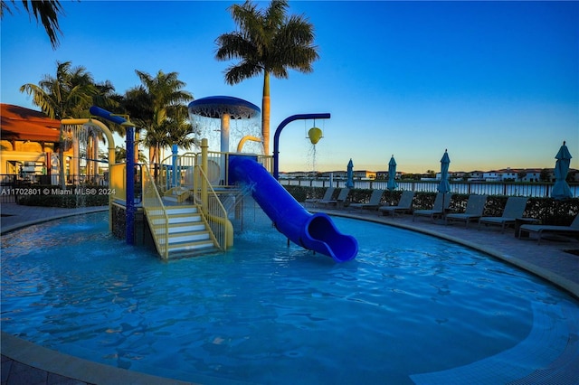 pool at dusk featuring a water slide