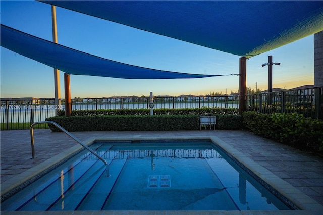 pool at dusk with a water view and a patio