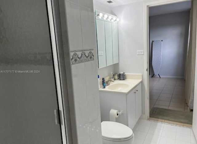 bathroom featuring tile patterned flooring, vanity, toilet, and an enclosed shower