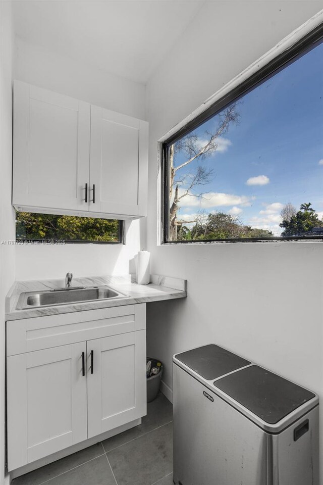 clothes washing area featuring sink, cabinets, and dark tile patterned flooring