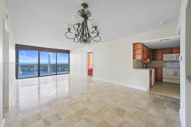 unfurnished living room featuring floor to ceiling windows, sink, an inviting chandelier, a textured ceiling, and a water view