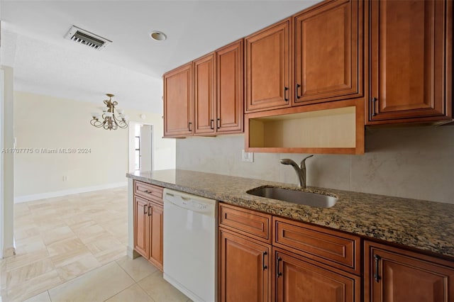 kitchen featuring dishwasher, dark stone counters, an inviting chandelier, sink, and decorative backsplash