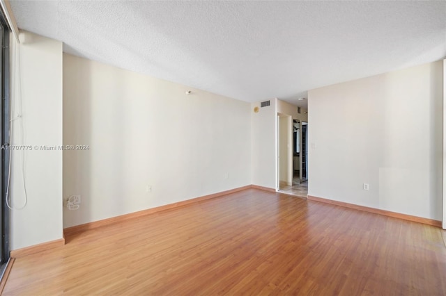 unfurnished room featuring hardwood / wood-style floors and a textured ceiling