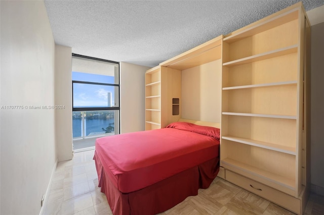 bedroom featuring a textured ceiling and a water view