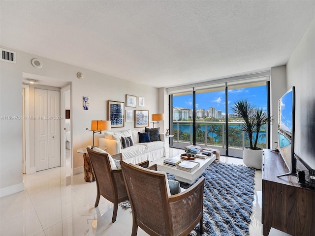 tiled living room featuring floor to ceiling windows and a textured ceiling