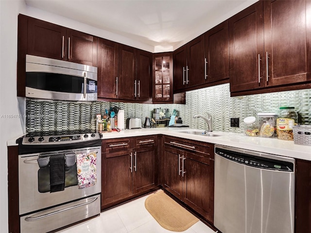 kitchen with appliances with stainless steel finishes, tasteful backsplash, dark brown cabinetry, sink, and light tile patterned floors