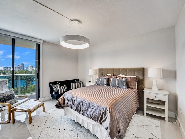 bedroom featuring floor to ceiling windows, a water view, and a textured ceiling