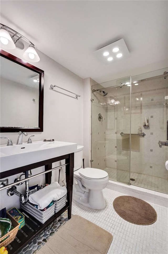 bathroom featuring tile patterned floors, toilet, and a shower with shower door