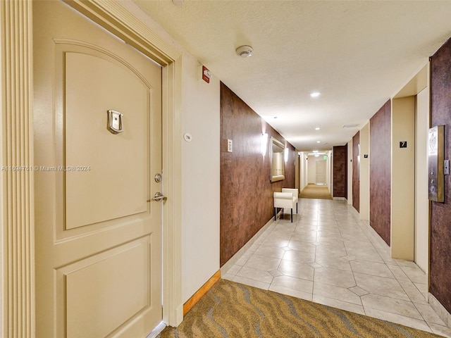 hallway featuring light tile patterned floors and a textured ceiling