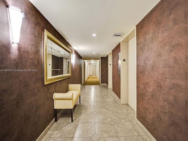 hall with light tile patterned flooring and a textured ceiling