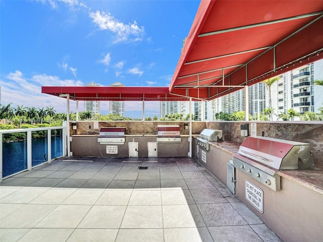 view of patio featuring a grill, a water view, and exterior kitchen