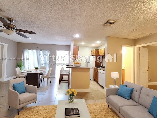 tiled living room featuring ceiling fan, sink, and a textured ceiling