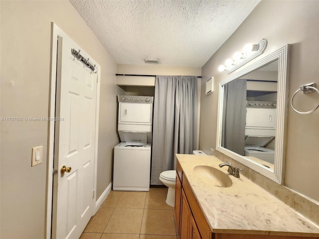 bathroom with tile patterned flooring, vanity, a textured ceiling, and stacked washer / dryer