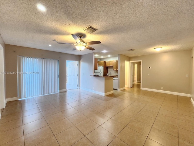 unfurnished living room featuring ceiling fan, light tile patterned floors, and a textured ceiling