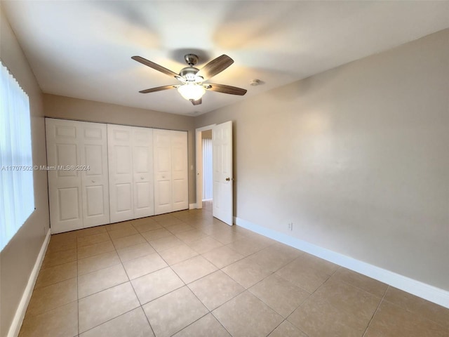 unfurnished bedroom featuring ceiling fan, a closet, and light tile patterned floors