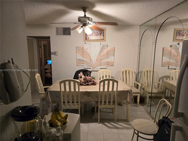 dining area with ceiling fan, light tile patterned floors, and a textured ceiling