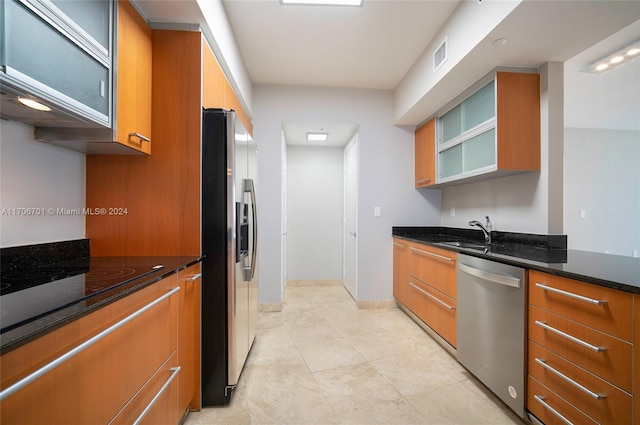 kitchen featuring sink, light tile patterned flooring, dark stone countertops, and stainless steel appliances