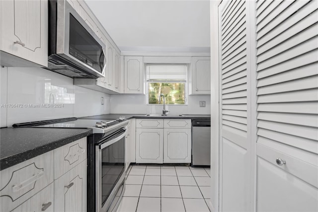 kitchen featuring sink, white cabinets, light tile patterned flooring, and appliances with stainless steel finishes