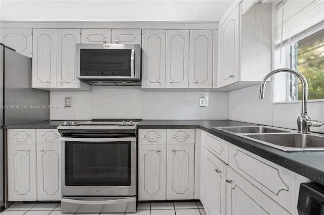 kitchen with white cabinets, light tile patterned floors, stainless steel appliances, and sink