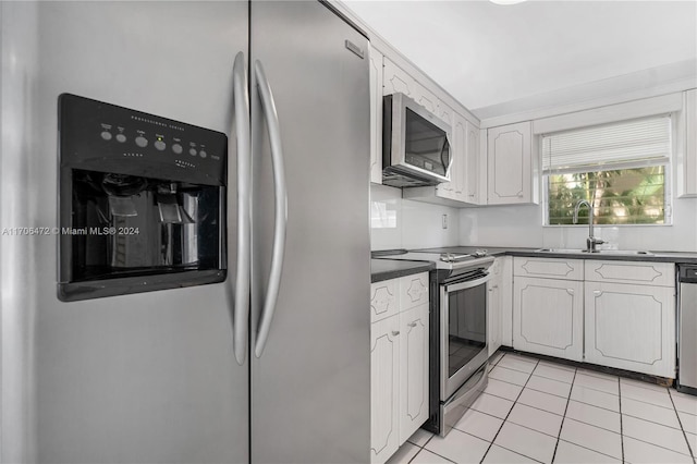 kitchen with light tile patterned floors, white cabinetry, sink, and appliances with stainless steel finishes